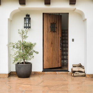 Foto di una porta d'ingresso mediterranea con pareti bianche, una porta singola, una porta in legno bruno e pavimento arancione