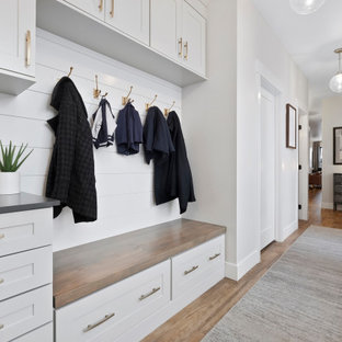 Cette image montre une entrée traditionnelle avec un vestiaire, un mur blanc, un sol marron et du lambris de bois.