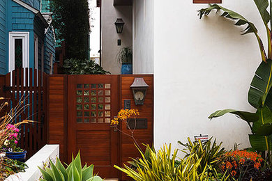 ロサンゼルスにある低価格の広いトロピカルスタイルのおしゃれな玄関ドア (白い壁、濃色木目調のドア) の写真