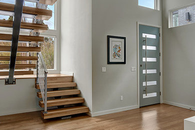 Modelo de distribuidor actual de tamaño medio con puerta simple, paredes grises, suelo de madera en tonos medios y puerta azul