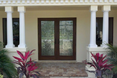 Diseño de puerta principal mediterránea grande con paredes beige, puerta doble, puerta de vidrio y suelo de ladrillo