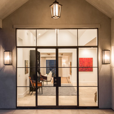 Huge transitional limestone floor entryway photo in Orange County with white walls and a metal front door