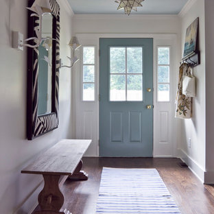 Aménagement d'une entrée éclectique avec un couloir, une porte simple, une porte bleue et un sol marron.