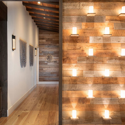 Example of a large mountain style medium tone wood floor and brown floor entryway design in Other with white walls and a dark wood front door