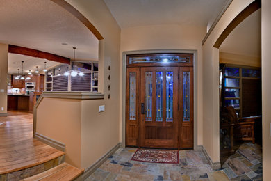 カルガリーにあるラグジュアリーな広いトラディショナルスタイルのおしゃれな玄関ロビー (ベージュの壁、スレートの床、濃色木目調のドア) の写真