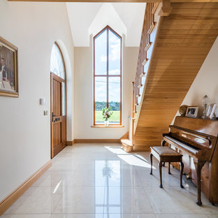 Ejemplo de hall clásico, grande, con puerta simple, puerta de madera en tonos medios, suelo de baldosas de porcelana, paredes beige y suelo blanco
