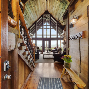 Cette image montre un hall d'entrée chalet en bois de taille moyenne avec un sol en bois brun, une porte double, un sol marron et un plafond voûté.