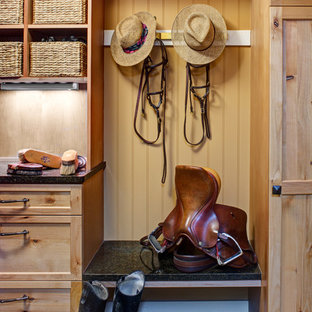 Réalisation d'une entrée chalet de taille moyenne avec un vestiaire, un mur marron, béton au sol, une porte simple, une porte en bois clair et un sol vert.