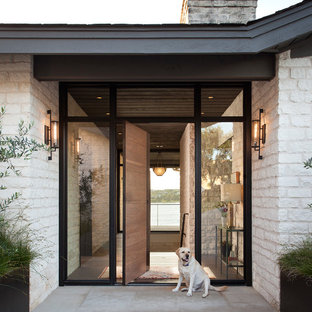 Ispirazione per una porta d'ingresso contemporanea con pareti bianche, una porta a pivot, una porta in legno bruno e pavimento grigio