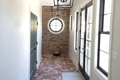 他の地域にある高級な中くらいなトランジショナルスタイルのおしゃれな玄関ロビー (白い壁、レンガの床、黒いドア) の写真