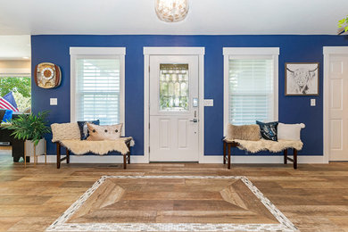 他の地域にあるカントリー風のおしゃれな玄関ロビー (青い壁、無垢フローリング、白いドア、茶色い床) の写真