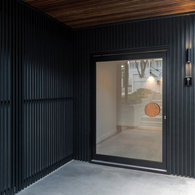 Example of a trendy concrete floor entryway design with black walls and a black front door