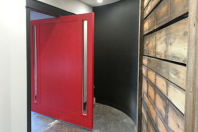 トロントにある広いコンテンポラリースタイルのおしゃれな玄関ドア (黒い壁、赤いドア、グレーの床) の写真