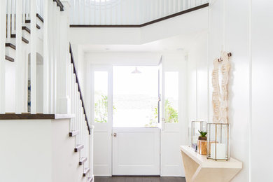 Photo of a coastal foyer in Orange County with white walls, dark hardwood flooring, a stable front door, a white front door and brown floors.