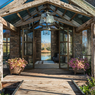 Inspiration pour une grand porte d'entrée chalet avec un sol en contreplaqué, une porte double, une porte métallisée et un mur beige.