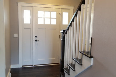 Modelo de entrada tradicional con paredes grises, suelo de madera oscura, puerta simple, puerta blanca y suelo marrón