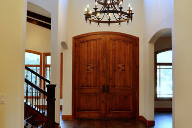 Imagen de puerta principal rústica con paredes beige, suelo de madera oscura, puerta doble y puerta de madera en tonos medios