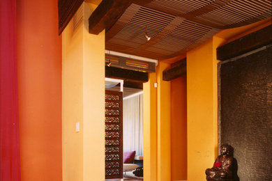 Idée de décoration pour une entrée asiatique avec un mur orange et parquet foncé.