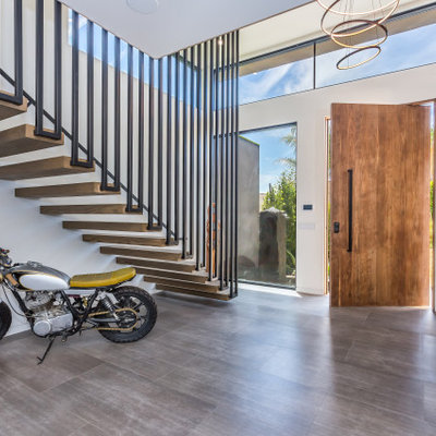 Large trendy gray floor entryway photo in Los Angeles with white walls and a medium wood front door