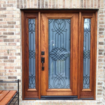 Mahogany entry door with matching sidelites and decorative iron work.