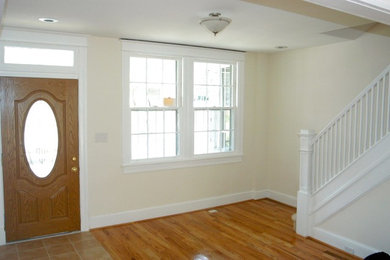 Elegant medium tone wood floor single front door photo in DC Metro with beige walls and a medium wood front door