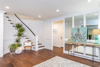 Large beach style dark wood floor and brown floor entryway photo in Los Angeles with white walls and a white front door