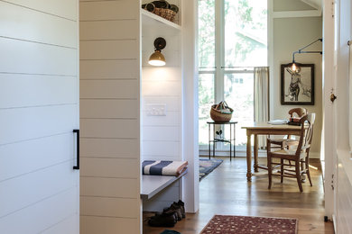 Example of a cottage light wood floor entryway design in New York with white walls