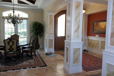 タンパにある高級な中くらいな地中海スタイルのおしゃれな玄関ロビー (ベージュの壁、トラバーチンの床、木目調のドア、ベージュの床) の写真