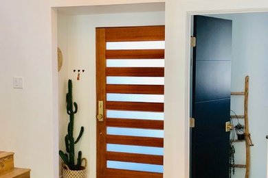 Ejemplo de puerta principal ecléctica grande con paredes blancas, suelo laminado, puerta simple, puerta de madera en tonos medios y suelo marrón