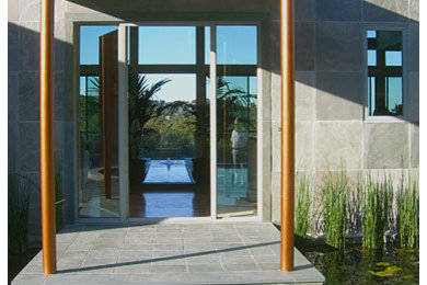 Inspiration pour une porte d'entrée design de taille moyenne avec un mur gris, sol en béton ciré, une porte simple et une porte grise.