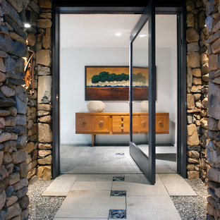 Idee per una porta d'ingresso minimal di medie dimensioni con una porta a pivot, una porta in vetro, pareti beige, pavimento in ardesia e pavimento beige