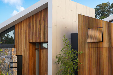 Cette image montre une grande porte d'entrée design avec une porte simple, une porte en bois brun, un mur marron et un sol gris.