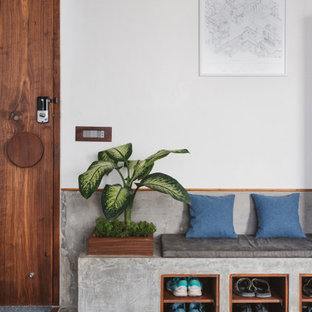 Modern inredning av en entré, med vita väggar, betonggolv, mellanmörk trädörr och grått golv