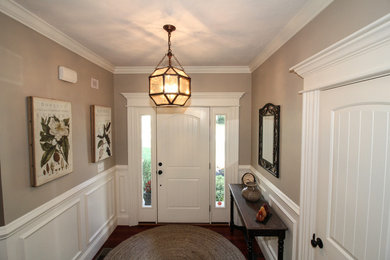 Entryway - small traditional medium tone wood floor entryway idea in Boston with beige walls and a white front door