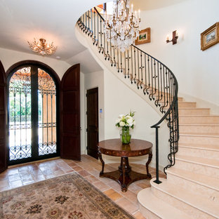 Diseño de distribuidor mediterráneo, grande, con puerta doble, puerta de madera oscura, paredes blancas y suelo de baldosas de cerámica