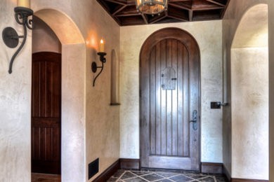 Inspiration for a mid-sized mediterranean marble floor and black floor entryway remodel in Los Angeles with brown walls and a dark wood front door