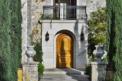 オレンジカウンティにある広い地中海スタイルのおしゃれな玄関ドア (淡色木目調のドア) の写真