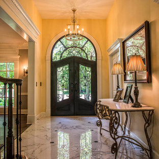 Large tuscan porcelain tile and white floor entryway photo in Kansas City with yellow walls and a black front door