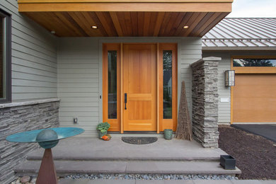 Imagen de puerta principal actual grande con paredes grises, suelo de pizarra, puerta simple y puerta de madera clara