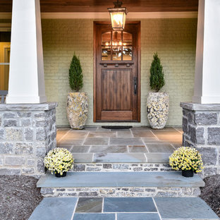 Immagine di una porta d'ingresso american style con pareti verdi, una porta singola, una porta in legno bruno e pavimento grigio