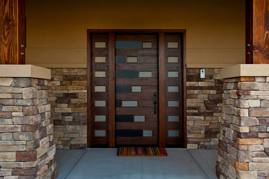 他の地域にある高級な広いコンテンポラリースタイルのおしゃれな玄関ドア (茶色い壁、コンクリートの床、濃色木目調のドア) の写真