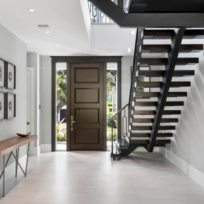 Example of a large trendy porcelain tile and white floor entryway design in Miami with gray walls and a dark wood front door