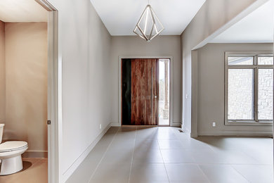 他の地域にある高級な中くらいなトランジショナルスタイルのおしゃれな玄関ロビー (ベージュの壁、磁器タイルの床、木目調のドア、ベージュの床) の写真