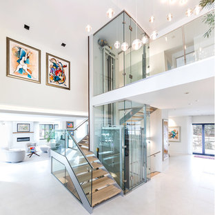 Cette photo montre un hall d'entrée tendance avec un mur blanc, un sol en carrelage de porcelaine, une porte pivot, une porte en bois foncé et un sol blanc.