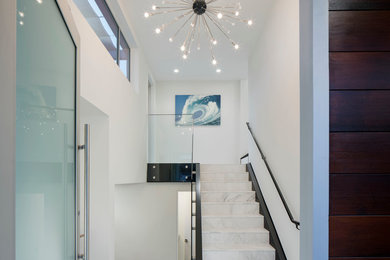 Entryway - contemporary marble floor entryway idea in San Diego with white walls and a glass front door