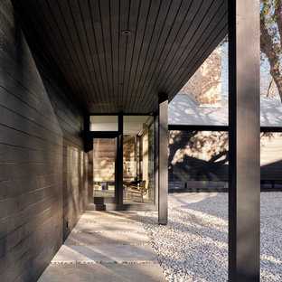 Réalisation d'une entrée minimaliste avec un vestiaire, un mur noir, une porte simple et une porte noire.