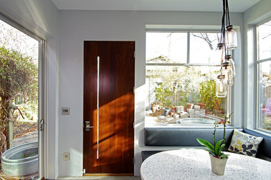 Diseño de puerta principal contemporánea de tamaño medio con paredes blancas, suelo de cemento, puerta simple y puerta de madera en tonos medios