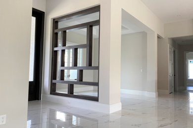 マイアミにある高級な小さなトランジショナルスタイルのおしゃれな玄関ロビー (ベージュの壁、磁器タイルの床、黒いドア、白い床) の写真
