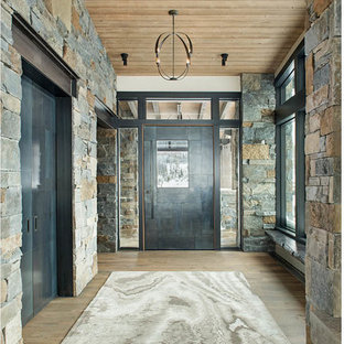 Ispirazione per una grande porta d'ingresso stile rurale con pareti grigie, una porta a pivot, una porta in metallo, pavimento marrone e pavimento in legno massello medio