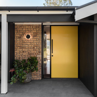 This is an example of a mid-sized midcentury front door in Other with grey walls, slate floors, a single front door, a yellow front door and grey floor.